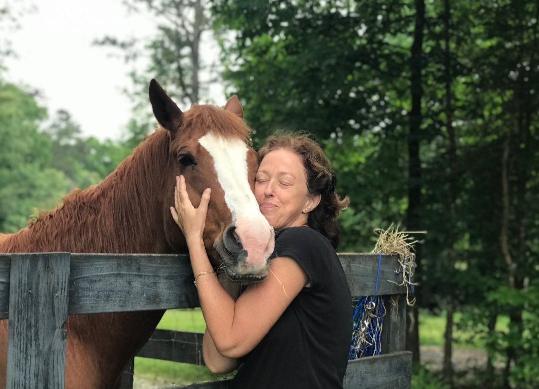 woman hugging brown horse